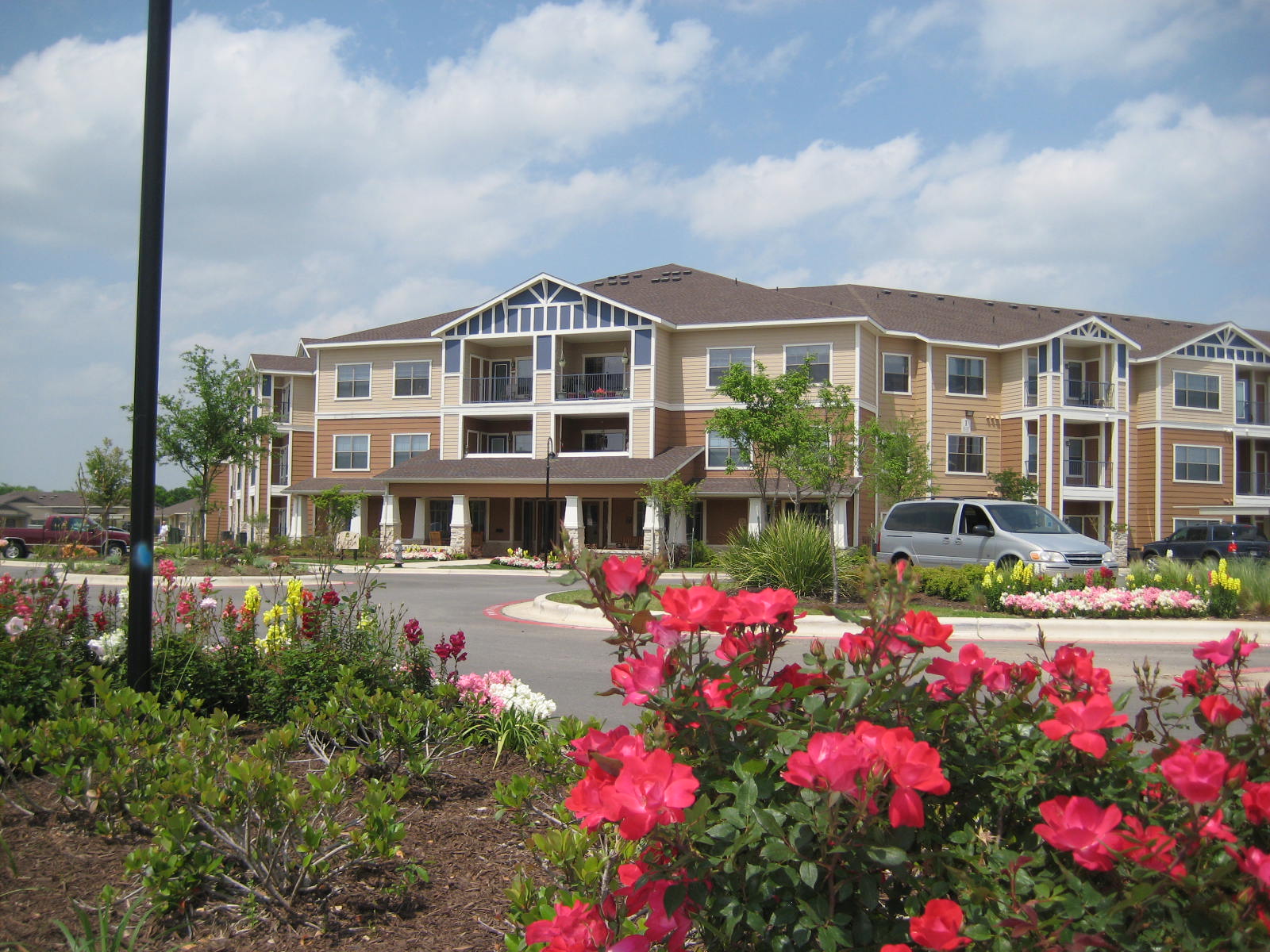 View of brown and white apartment complex through a close up of a pink flower bush